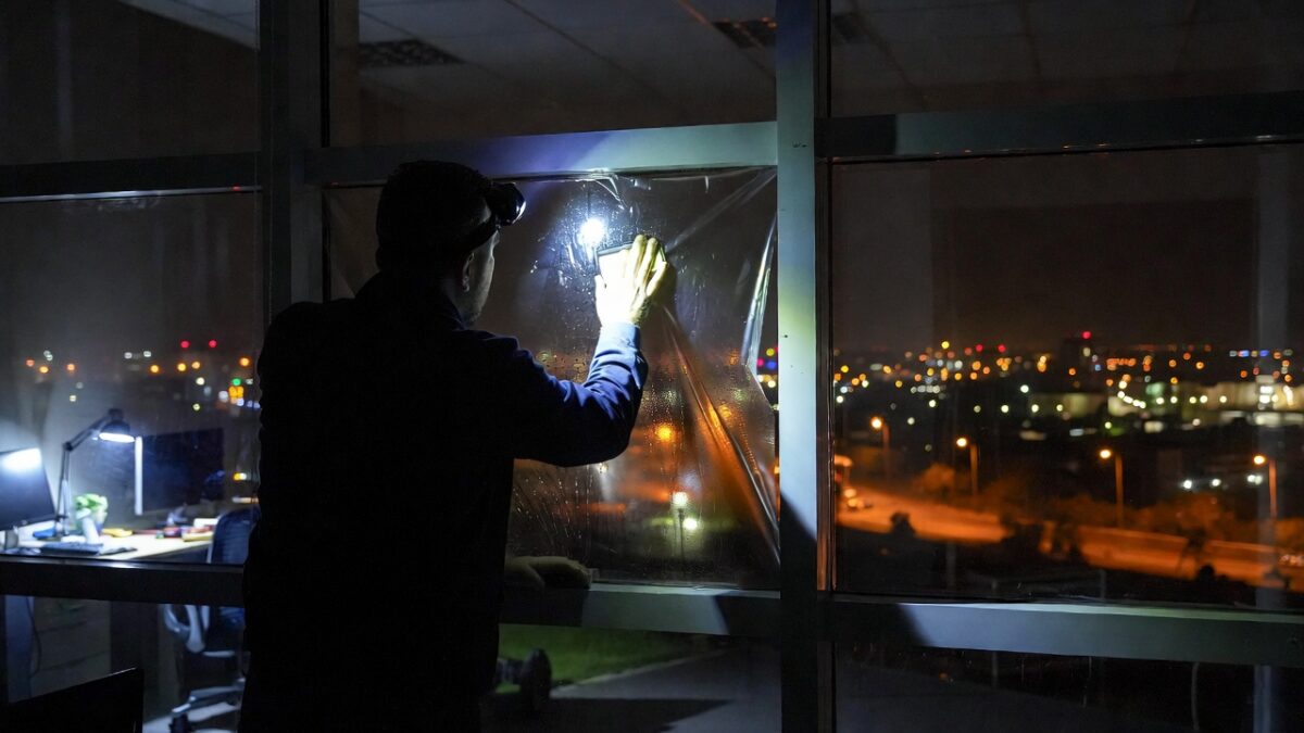 person-installing-window-film-at-night